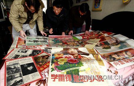 3月1日，房冠龍（中）在家中整理關(guān)于雷鋒的宣傳海報。